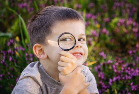 Gutt som ser gjennom et forstørrelsesglass